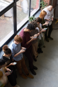 A Row of people sitting down and bent over their phones, meant to exemplify peer to peer fundraising.